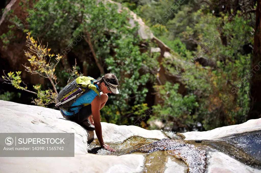 Female hiker crouching on rock, Mount Wilson, Red Rock Canyon, Nevada, USA