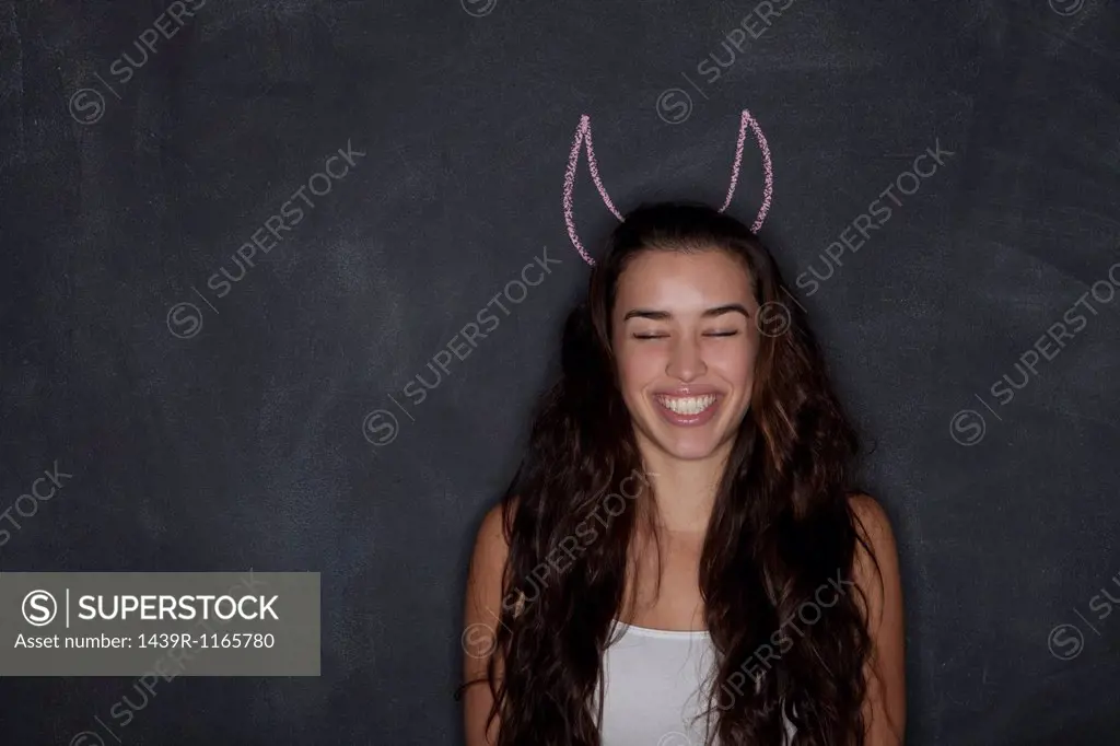 Young woman by blackboard with horns
