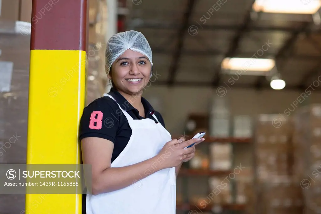 Portrait of female factory worker using cell phone