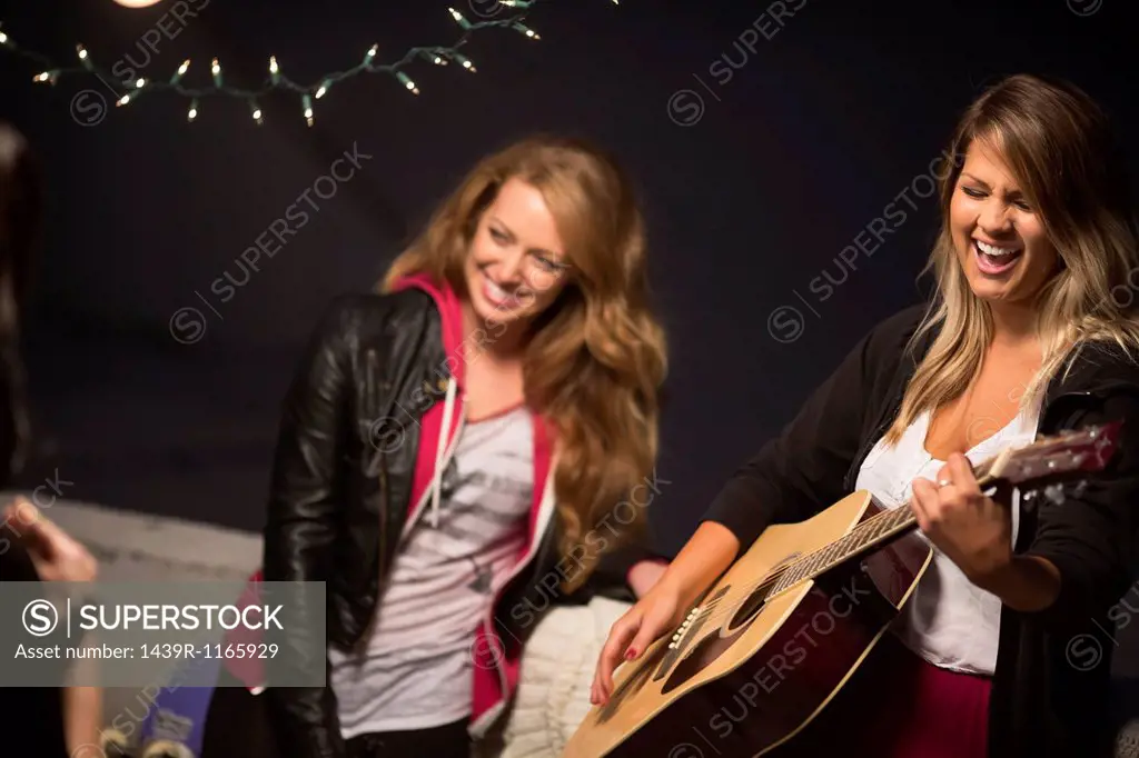 Female friends enjoying guitar music at rooftop party