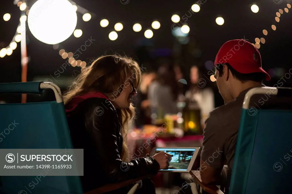 Young couple looking at digital tablet at rooftop barbecue