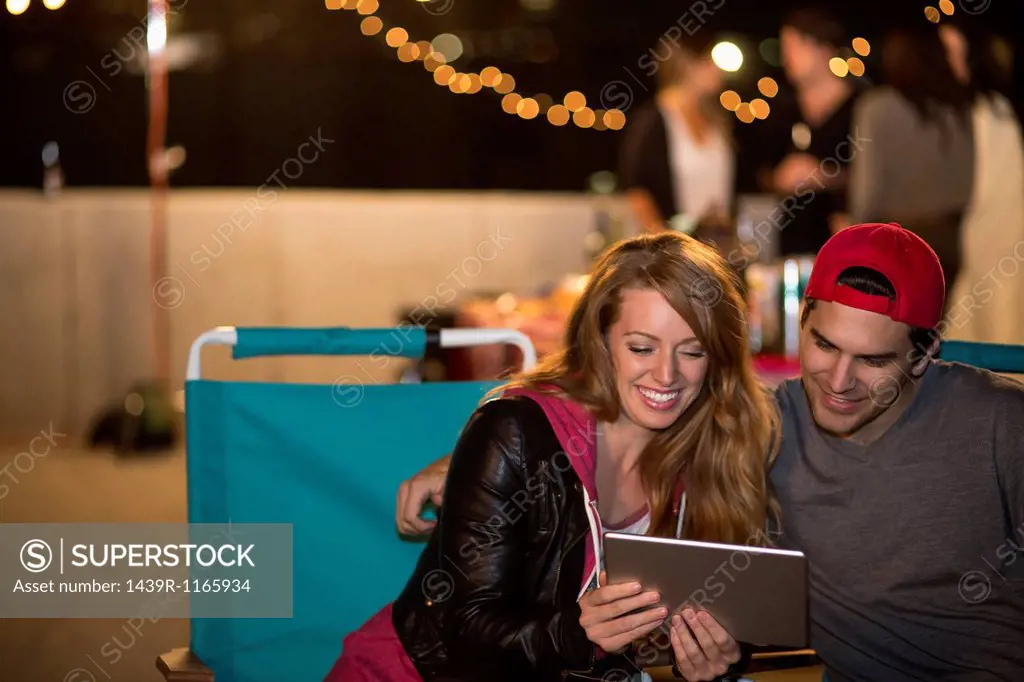 Young couple using digital tablet at rooftop barbecue