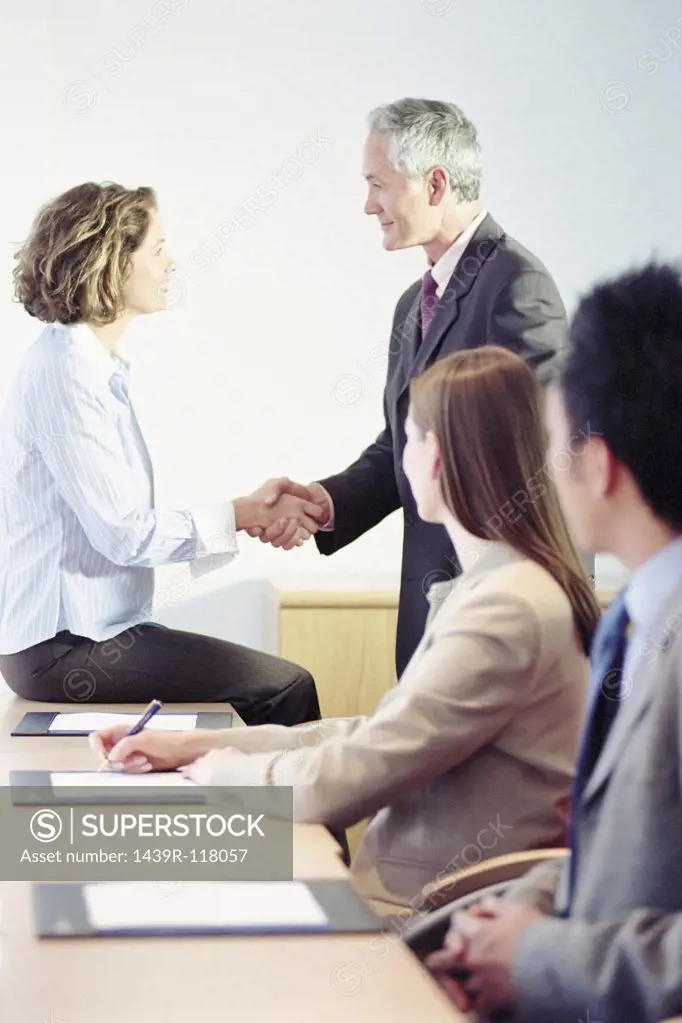 Businessman and businesswoman shaking hands in meeting