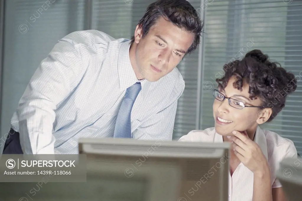 Businessman and businesswoman looking at computer screen