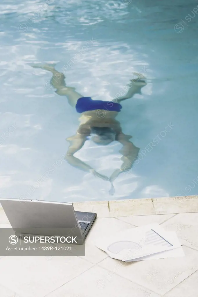 Man in swimming pool with computer