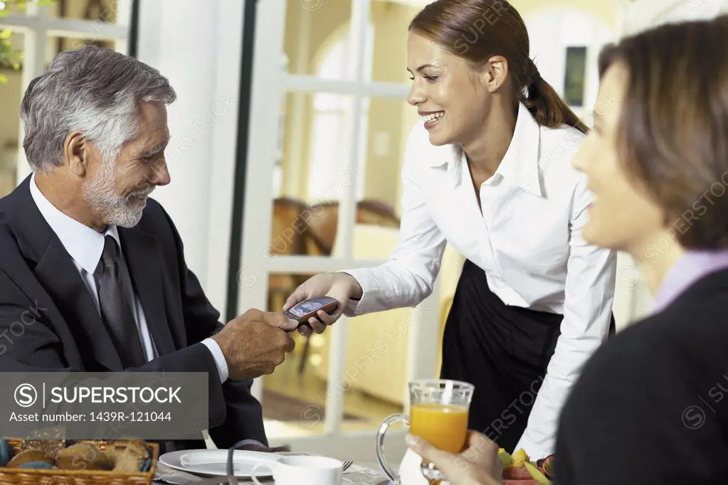 Waitress handing cellphone to businessman