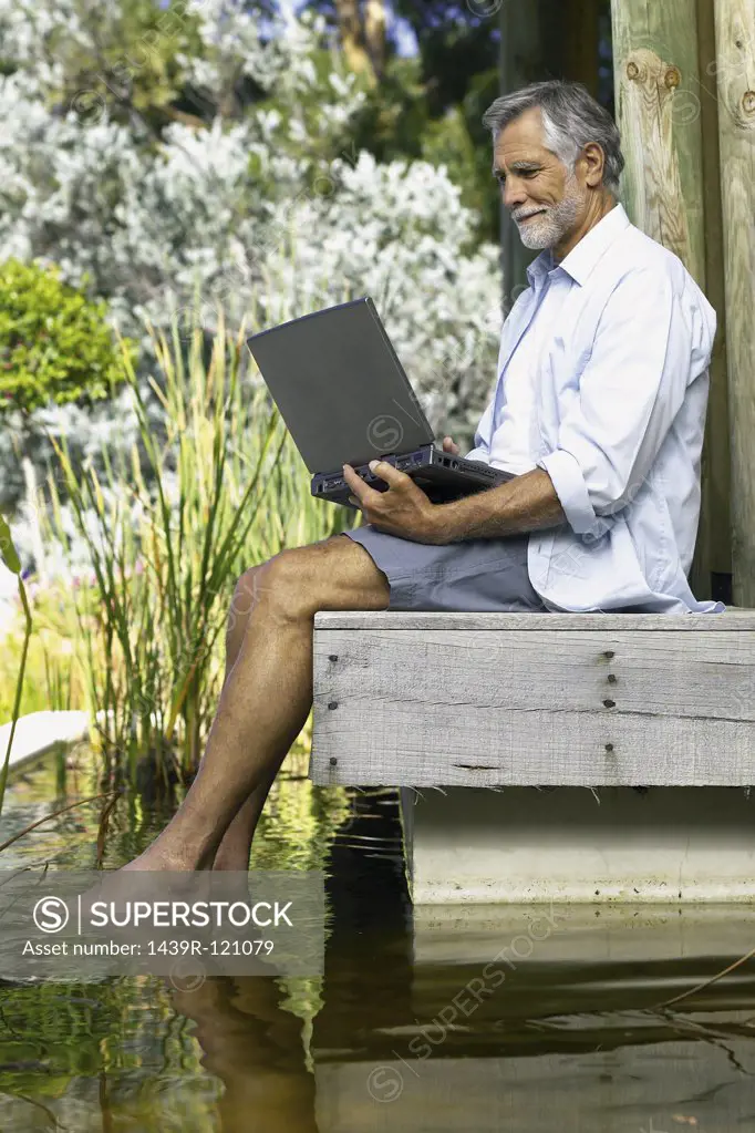 Man beside pool with computer