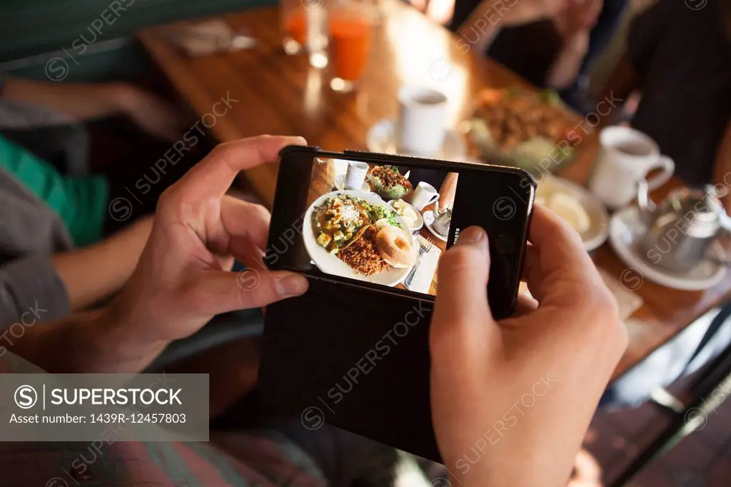 Cropped shot of man taking photograph of meal in vegetarian restaurant