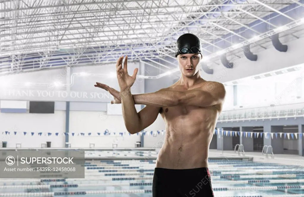 Male swimmer stretching by swimming pool
