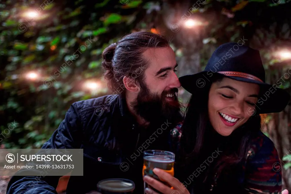 Young couple laughing in beer garden in evening, Brooklyn, New York, USA