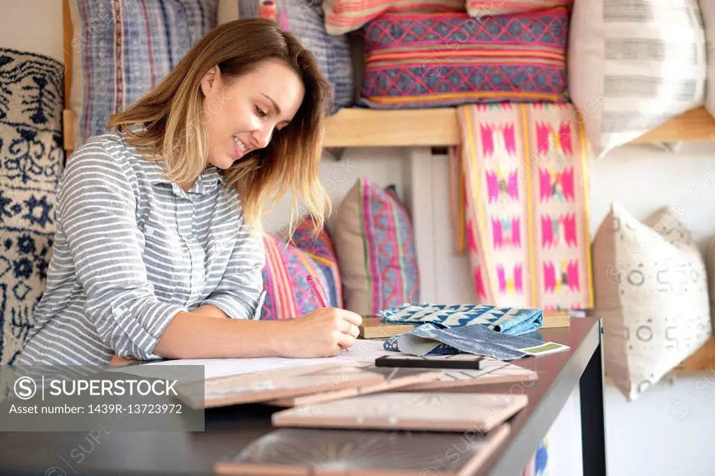 Female interior designer drawing designs at desk in retail studio