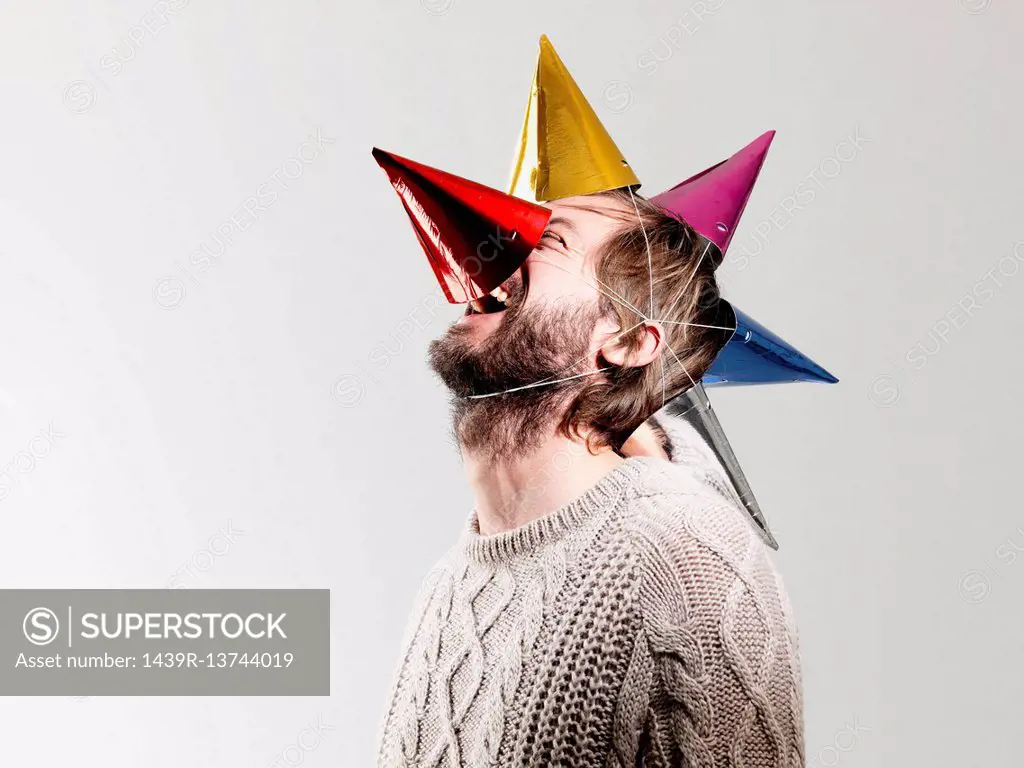 Mid adult man in party hats against white background
