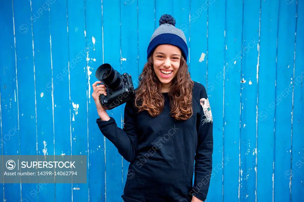 Girl with camera against blue wooden panelling background