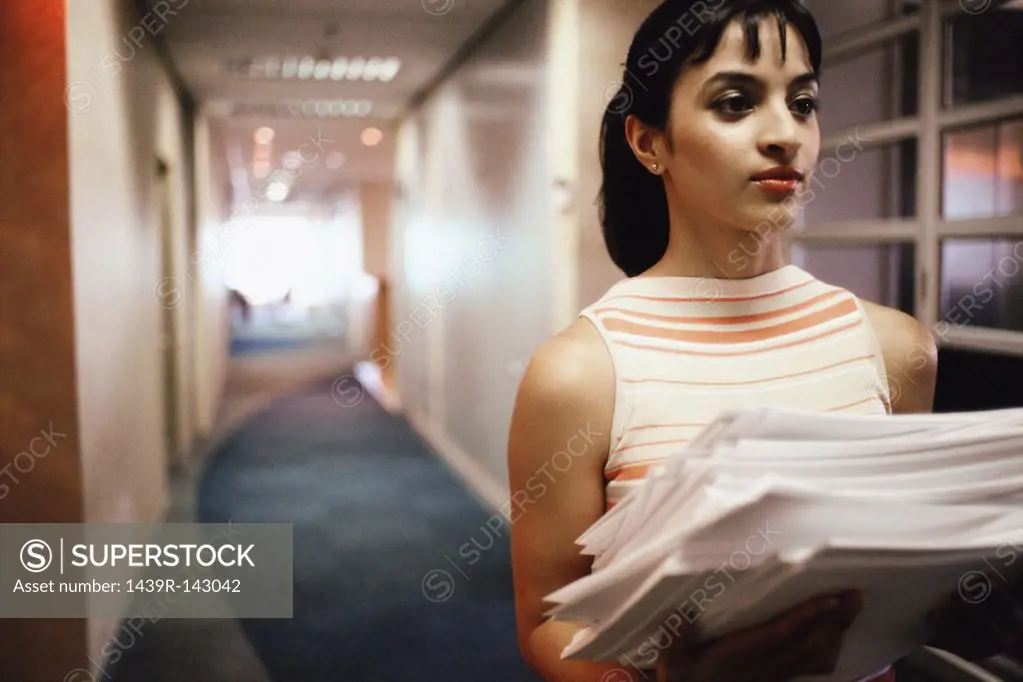 Woman carrying stack of paper