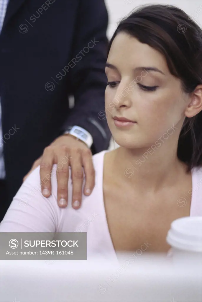 Woman looking at man's hand on her shoulder