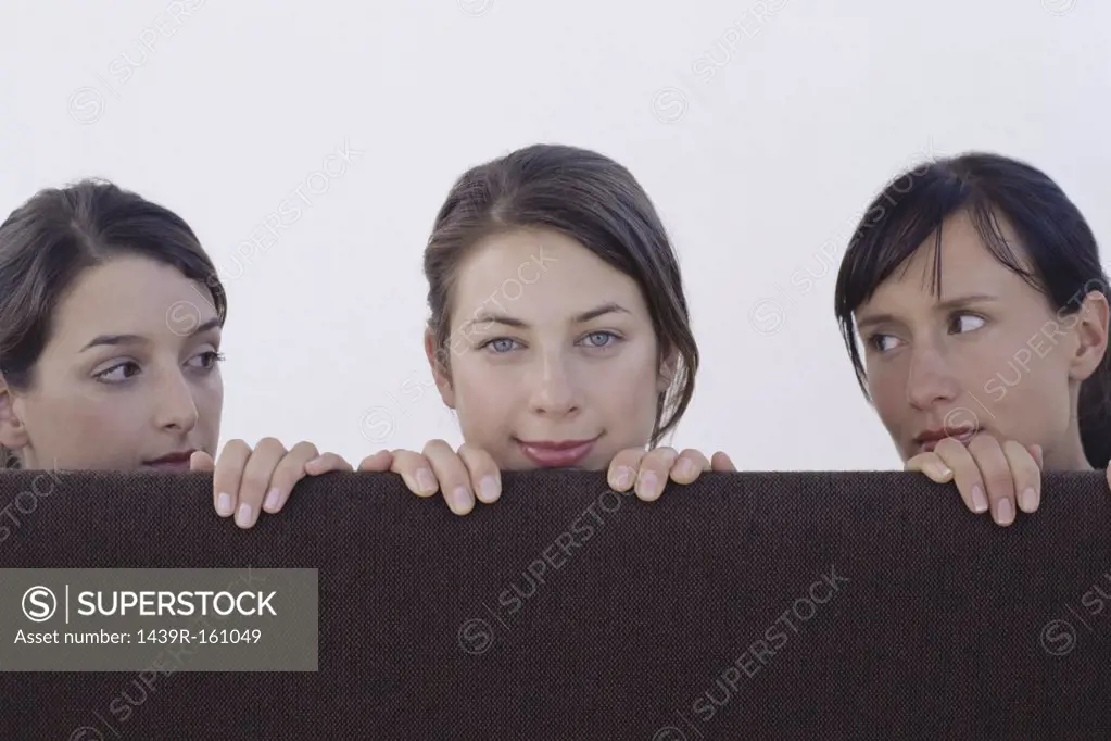 Three women looking over cubicle