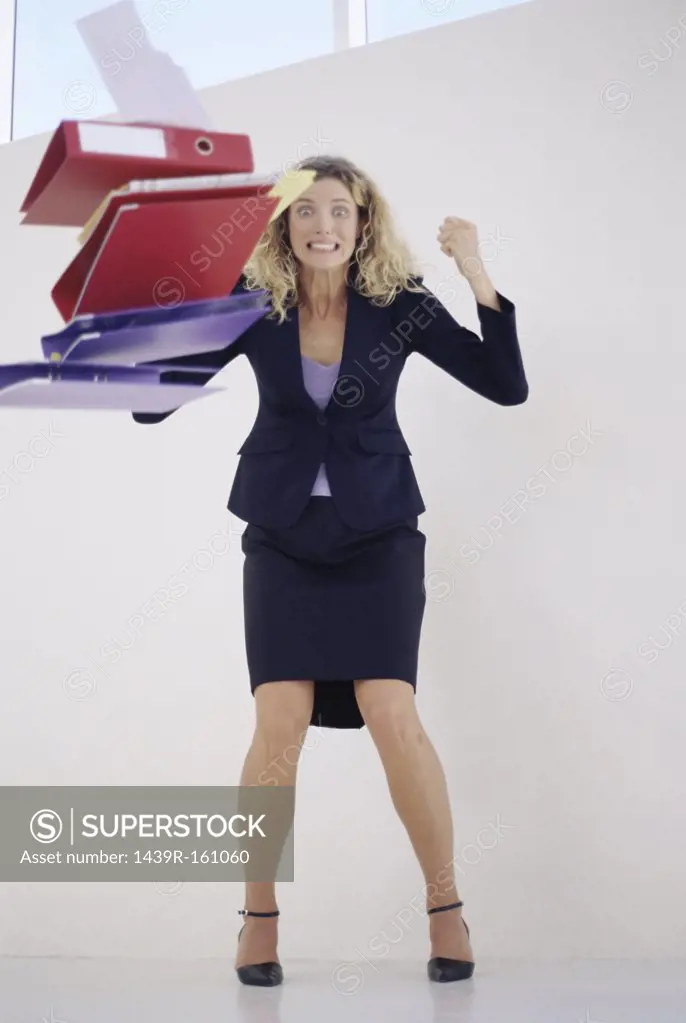Angry businesswoman throwing folders