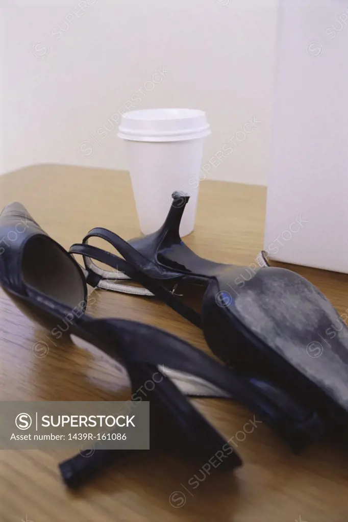 High heeled shoes and cup on a desk