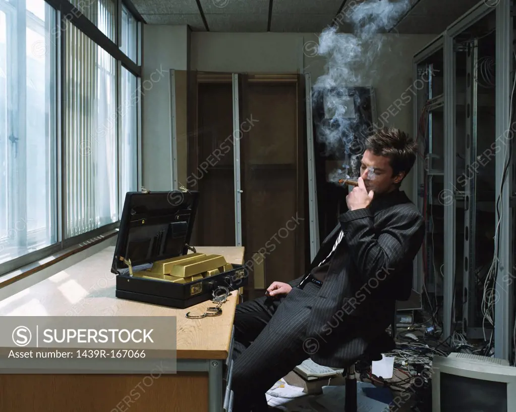 Man smoking a cigar with briefcase of gold bars 