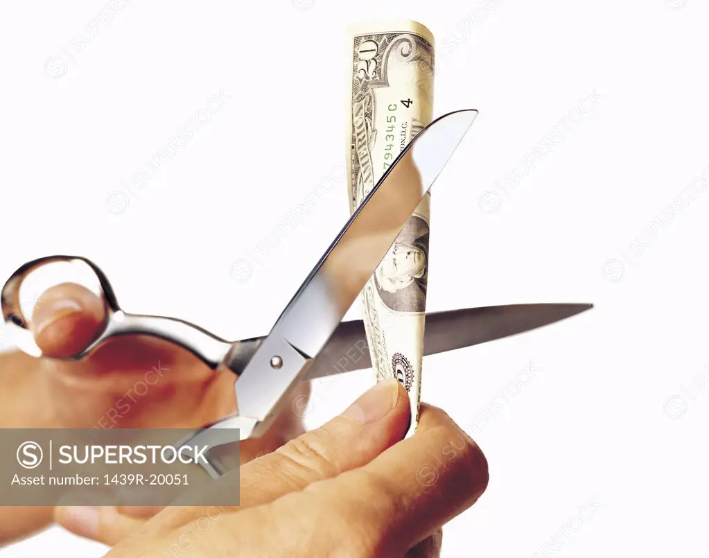 Person cutting a banknote with scissors
