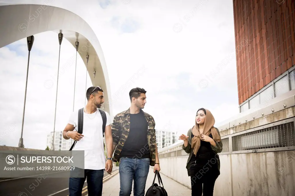 Three friends, walking across urban bridge