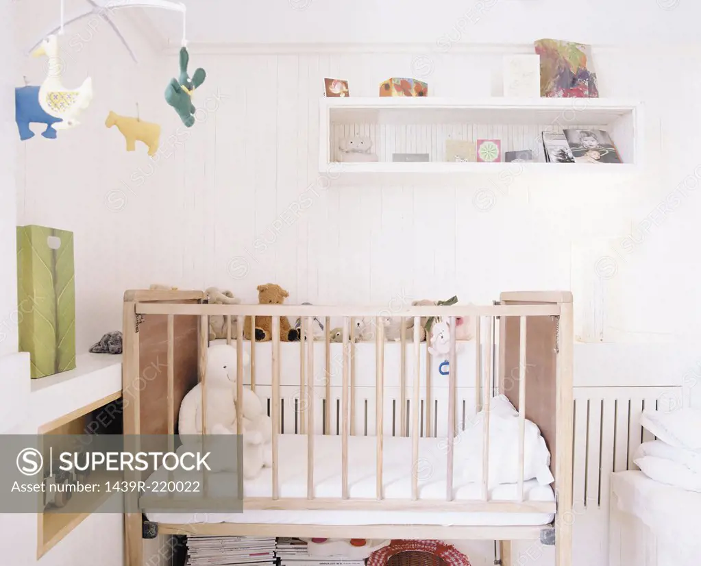 A baby's bedroom with teddy bears in the cot.