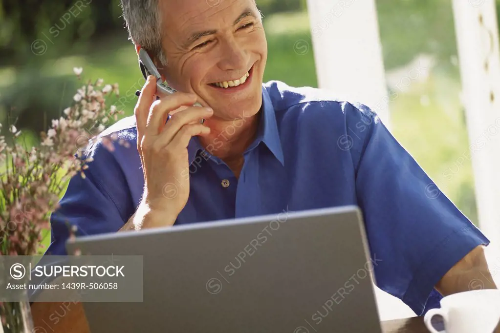 Man using laptop computer and cellphone