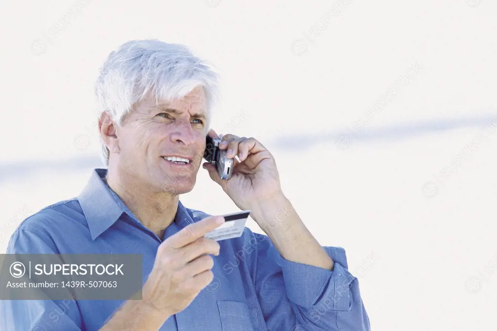 Man by the sea with cellphone and credit card