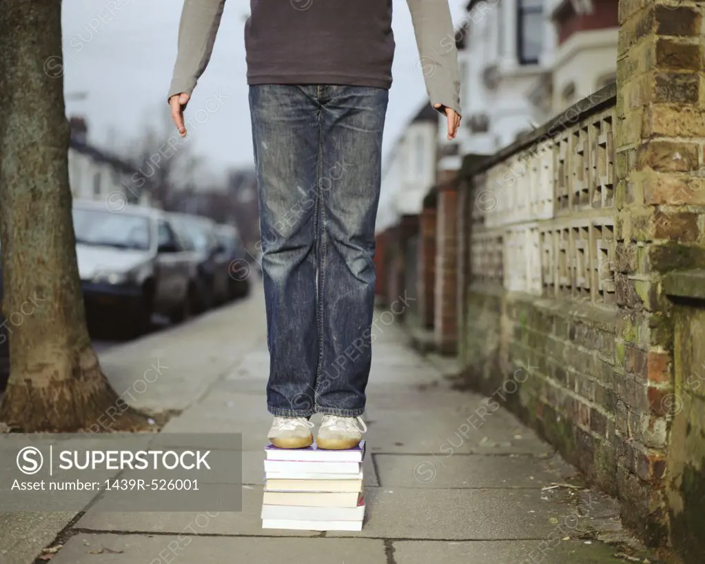 A young man standing on a pile of books
