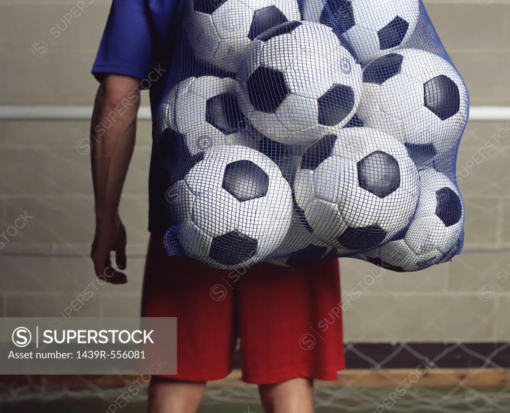 Footballer holding a bag of footballs