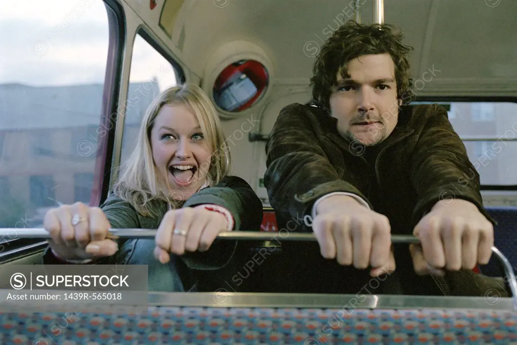 Couple grasping bus seat
