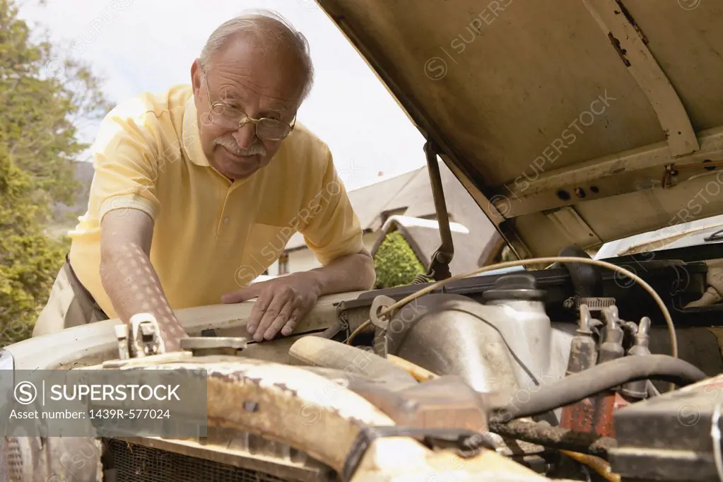 Older man looks at car engine