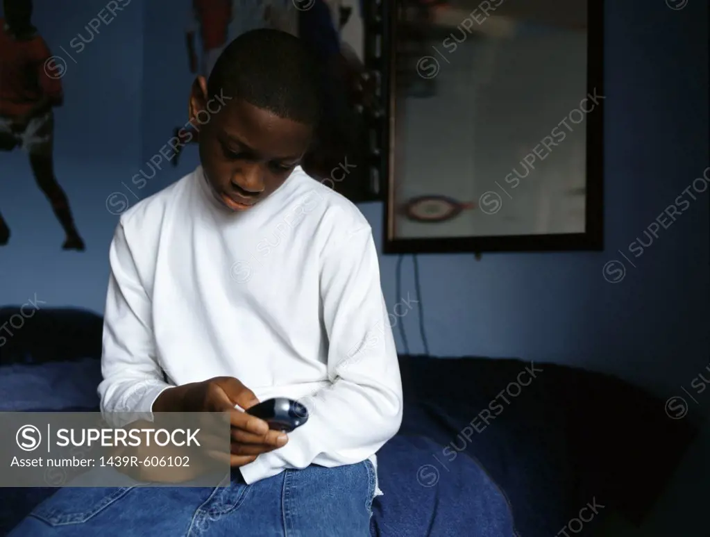 Boy text messaging in bedroom