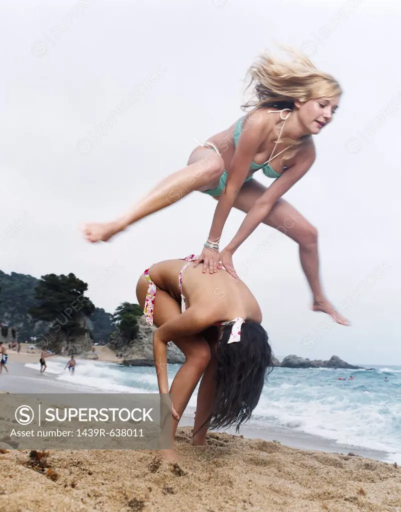 Women leapfrogging on beach