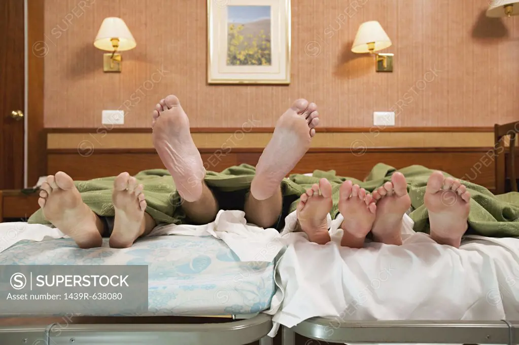 Four pairs of feet in a bed 