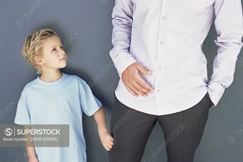 Boy pulling in father's trouser leg
