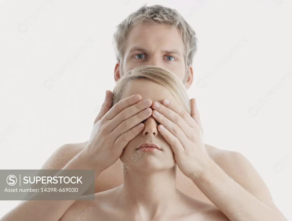 Man covering woman's eyes
