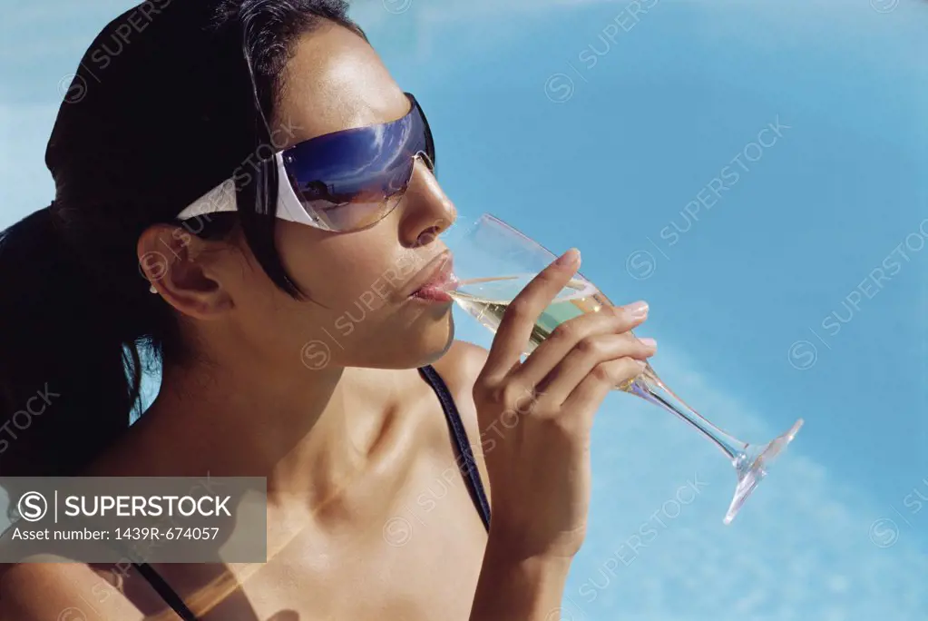 Woman drinking champagne by the pool