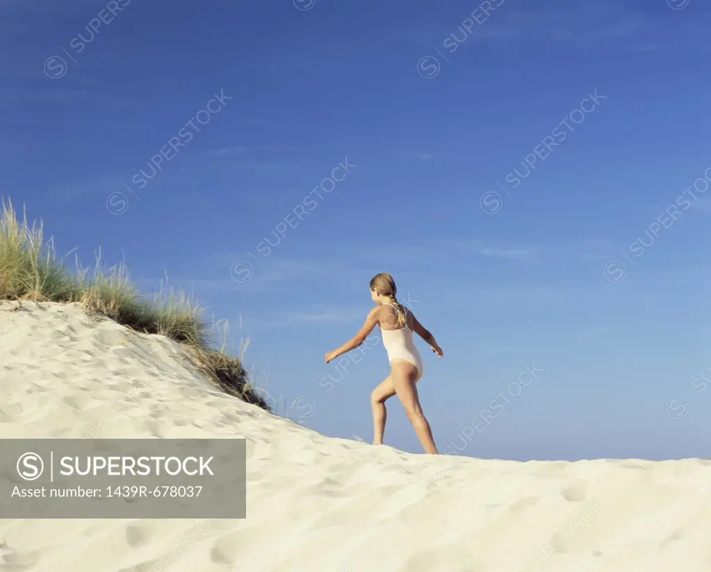 Girl walking up a sand dune