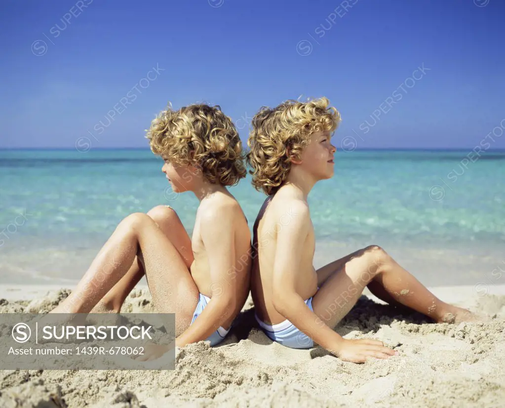 Twin boys sitting on the beach