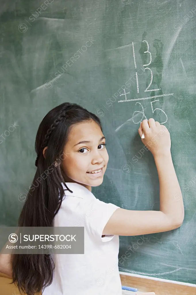 Girl writing a sum on a blackboard