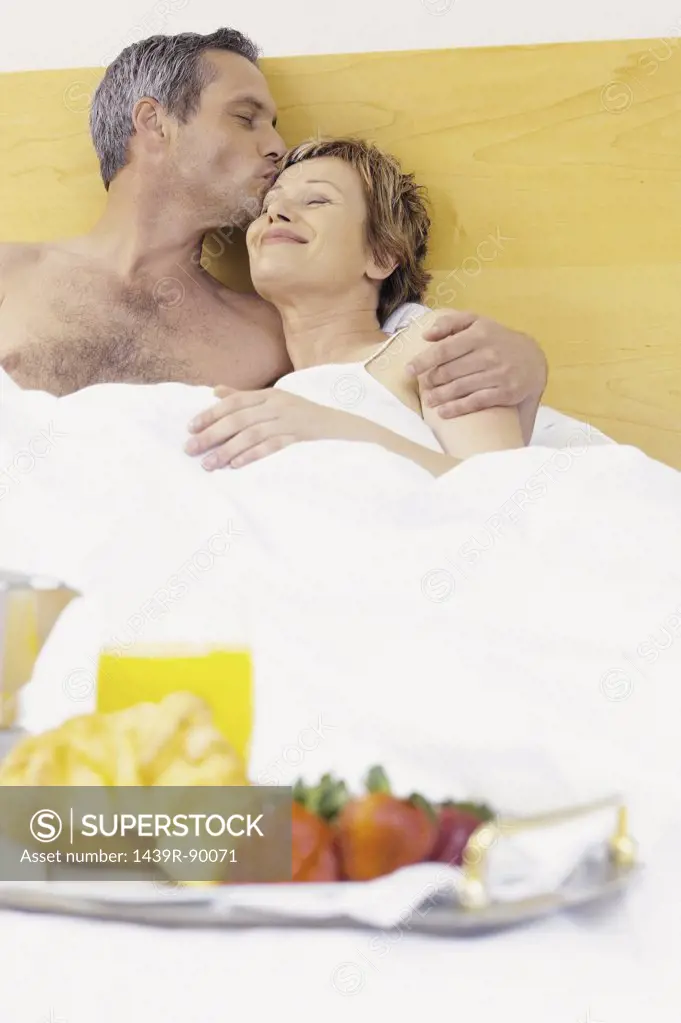 Man and woman having breakfast in bed