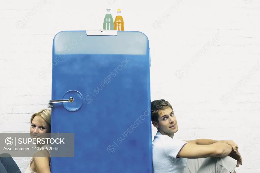 Couple seated against a fridge