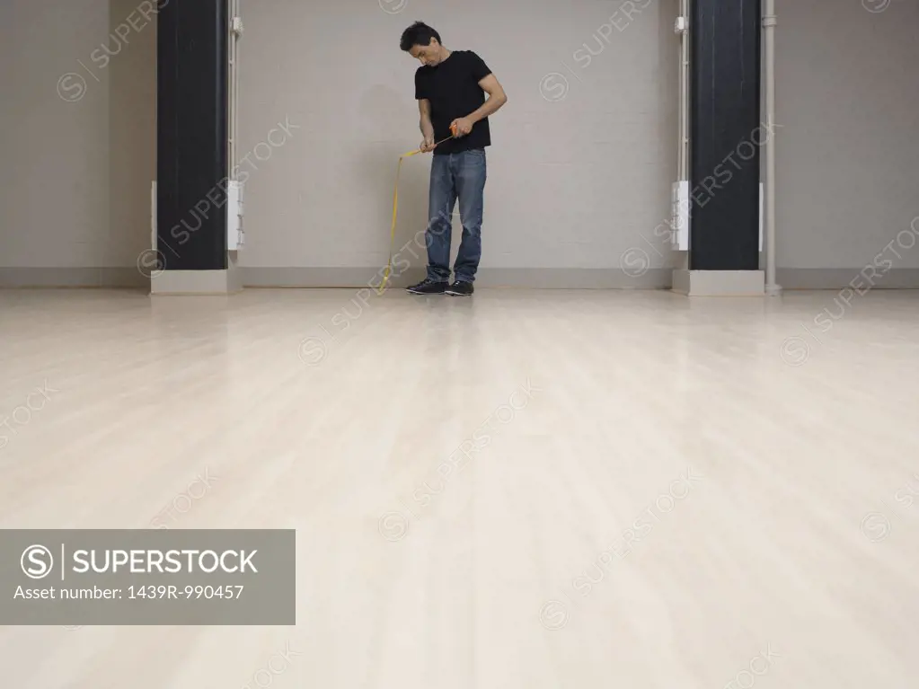 Man with tape measure in empty office space