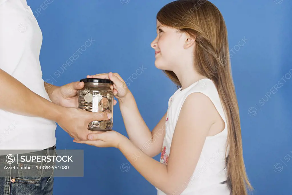 Girl handing jar of coins to mother