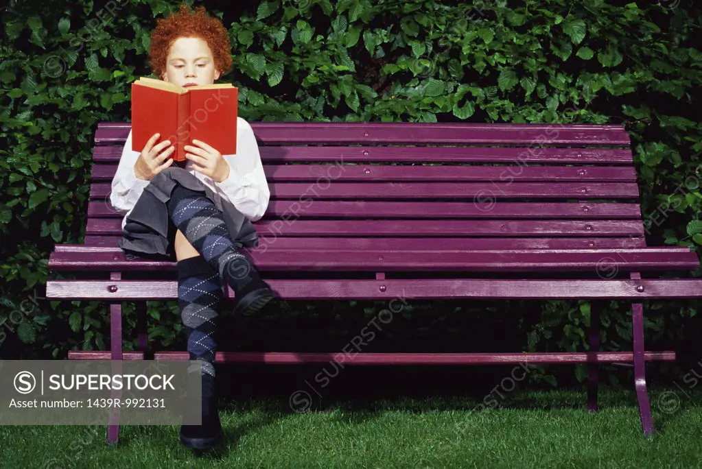 Girl on a bench reading a book