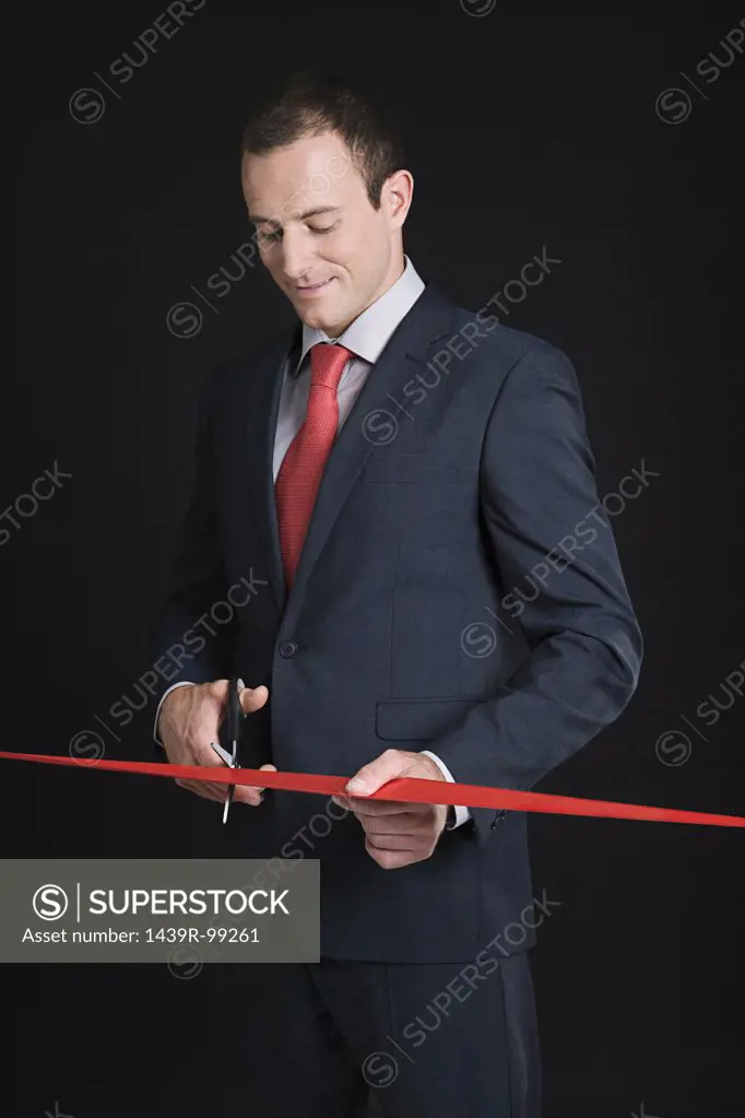 Businessman cutting a red ribbon