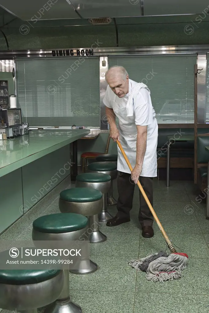 Old cleaner mopping a diner floor