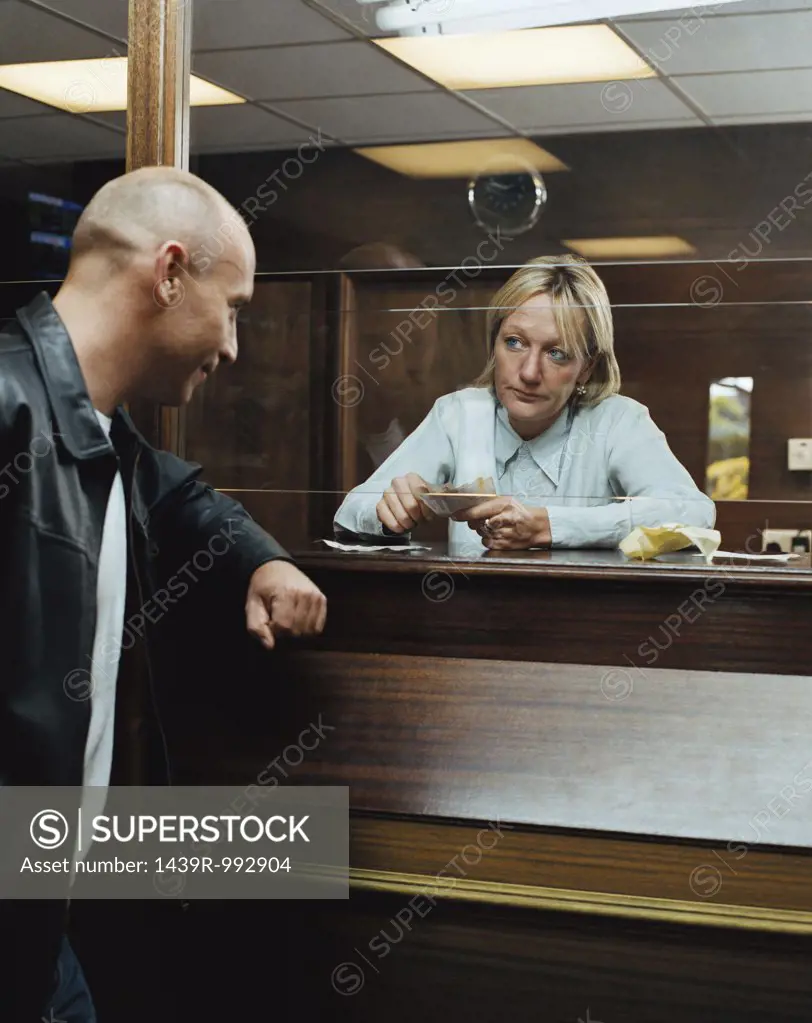 Betting shop worker counting money for customer