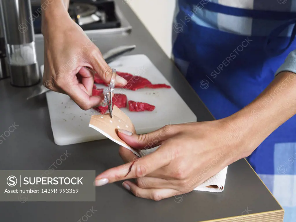 Woman cutting adhesive plaster to put on her finger